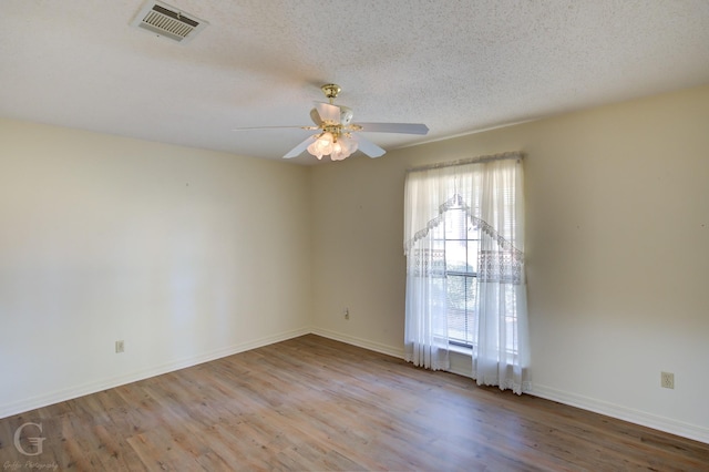 spare room with ceiling fan, light wood-type flooring, and a textured ceiling