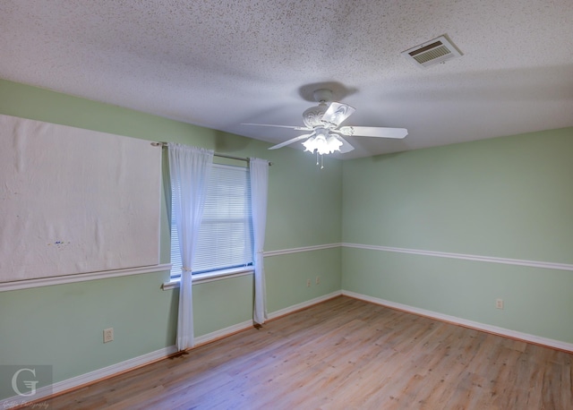 unfurnished room with ceiling fan, a textured ceiling, and light wood-type flooring