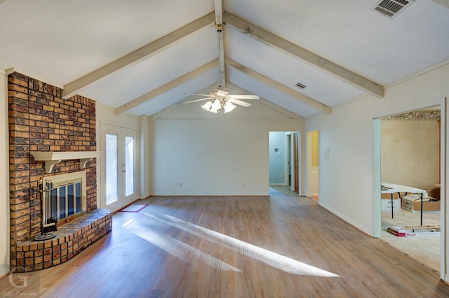 unfurnished living room featuring french doors, vaulted ceiling with beams, ceiling fan, a fireplace, and wood-type flooring