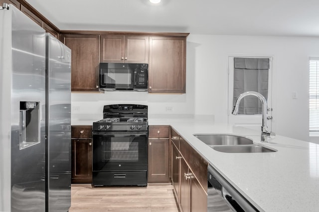 kitchen with light stone countertops, sink, light hardwood / wood-style flooring, and black appliances