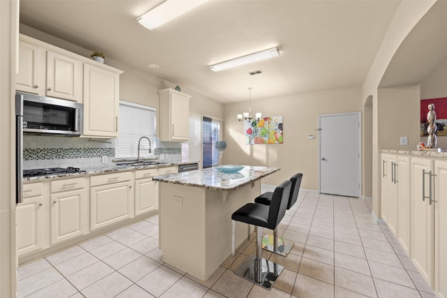 kitchen featuring decorative backsplash, a center island, light stone countertops, and appliances with stainless steel finishes