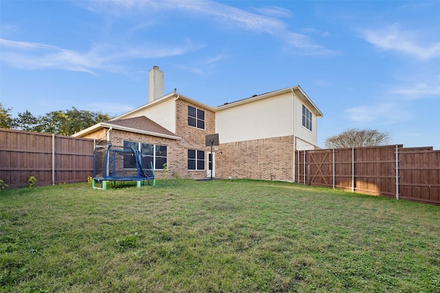 back of house featuring a yard and a trampoline