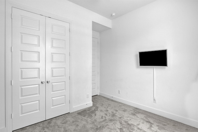 unfurnished bedroom featuring light carpet and a closet