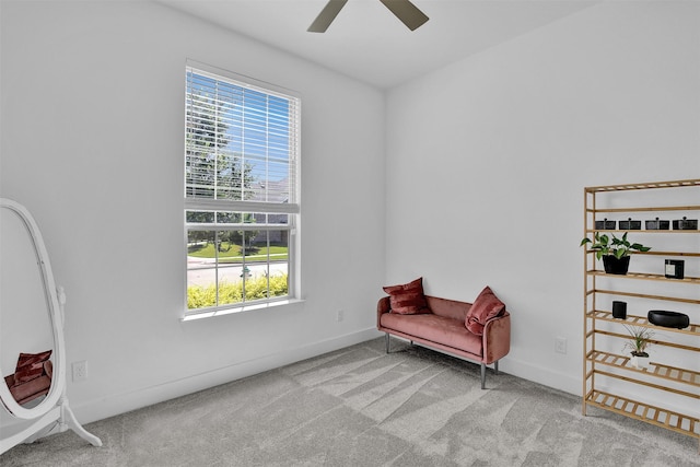 living area with a wealth of natural light, ceiling fan, and light colored carpet