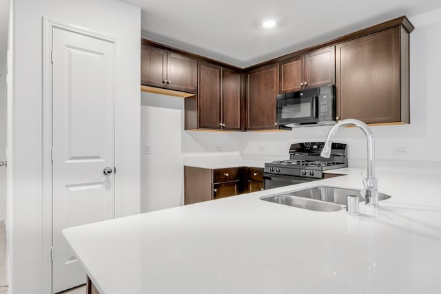 kitchen with sink, dark brown cabinets, stainless steel range with gas stovetop, and kitchen peninsula