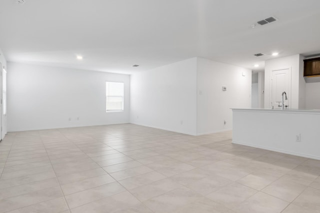 unfurnished living room featuring sink and light tile patterned floors