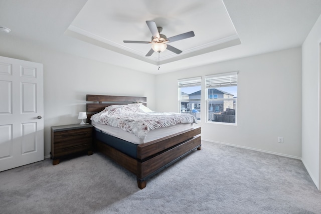 carpeted bedroom with ceiling fan, ornamental molding, and a raised ceiling