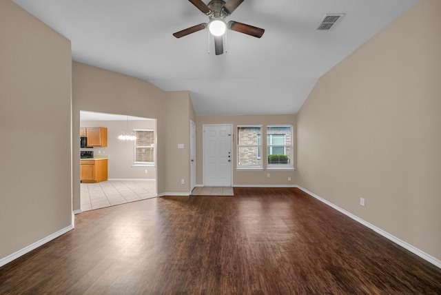 unfurnished living room with lofted ceiling, ceiling fan with notable chandelier, and light hardwood / wood-style floors