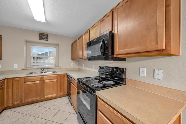 kitchen featuring sink, a textured ceiling, light tile patterned floors, kitchen peninsula, and black appliances