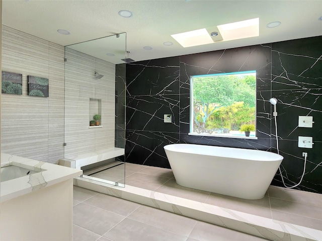 bathroom with tile patterned floors, separate shower and tub, vanity, and tile walls