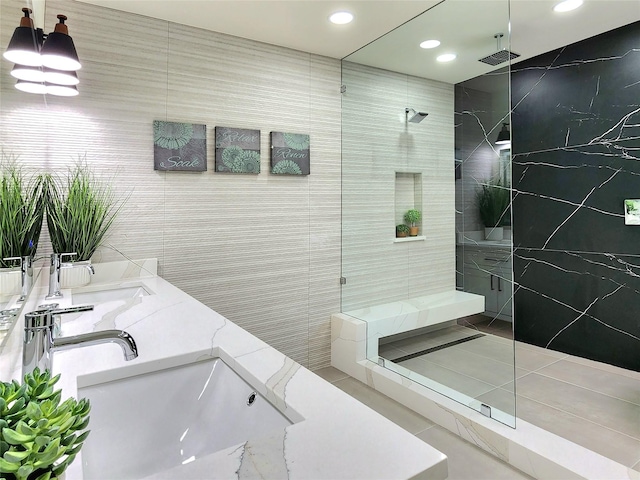 bathroom with a shower, vanity, tile patterned floors, and tile walls