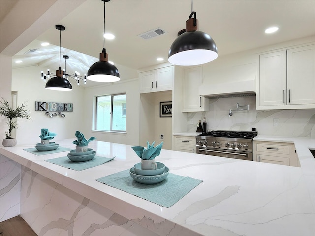 kitchen featuring pendant lighting, high end stainless steel range oven, tasteful backsplash, custom range hood, and white cabinets