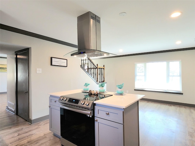 kitchen featuring stainless steel electric stove, a kitchen island, crown molding, and island exhaust hood