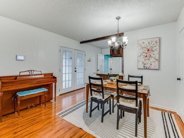 dining area featuring a chandelier, a textured ceiling, light hardwood / wood-style flooring, and beamed ceiling