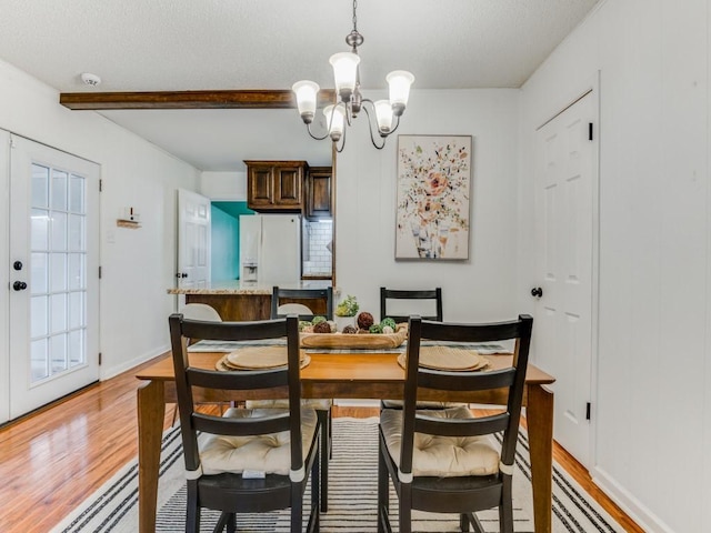 dining space with a chandelier, hardwood / wood-style floors, a wealth of natural light, and beam ceiling