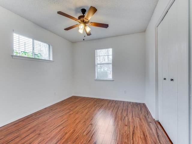 unfurnished room featuring hardwood / wood-style flooring, a wealth of natural light, a textured ceiling, and ceiling fan