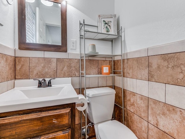 bathroom with vanity, tile walls, and toilet