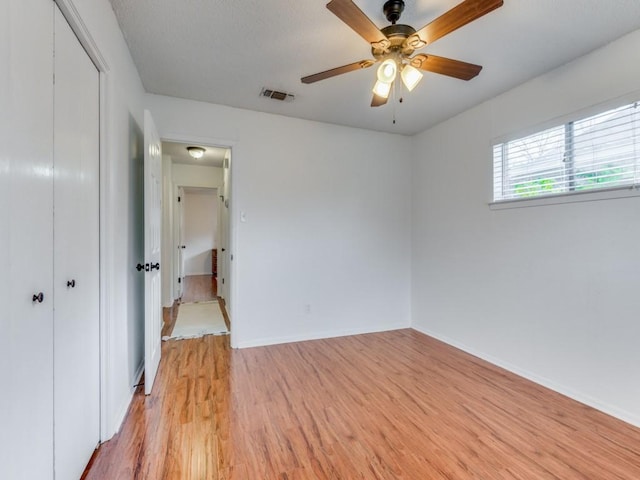 unfurnished bedroom featuring ceiling fan, light wood-type flooring, and a closet