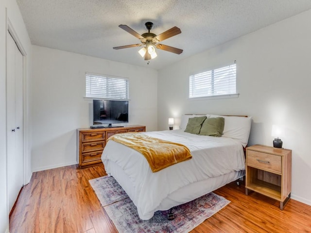 bedroom featuring ceiling fan, light hardwood / wood-style floors, a textured ceiling, and a closet