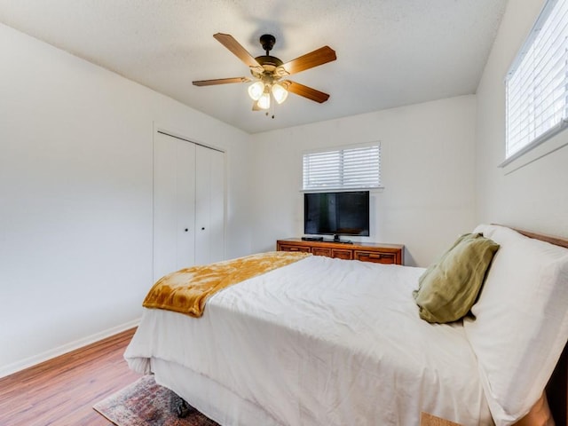 bedroom with ceiling fan, light wood-type flooring, and a closet