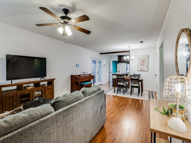 living room with hardwood / wood-style flooring, ceiling fan with notable chandelier, and a textured ceiling