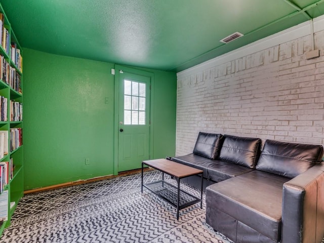 living room featuring brick wall and a textured ceiling