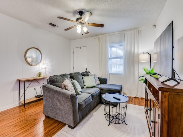 living room with a textured ceiling, hardwood / wood-style flooring, and ceiling fan