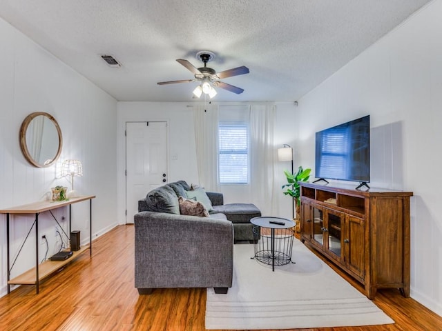 living room featuring ceiling fan, wood-type flooring, and a textured ceiling