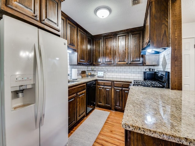 kitchen featuring light stone countertops, decorative backsplash, dark brown cabinets, black appliances, and light hardwood / wood-style flooring