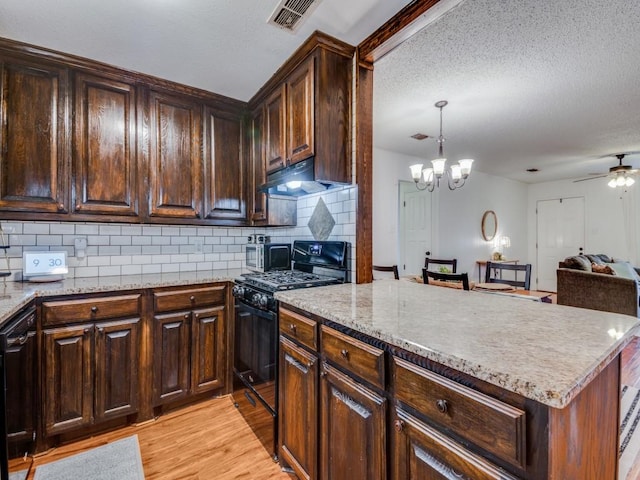 kitchen with decorative light fixtures, light hardwood / wood-style flooring, dark brown cabinetry, and black appliances