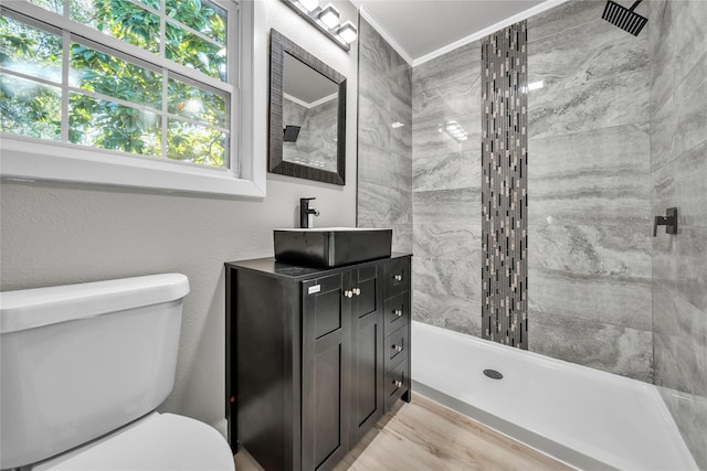 bathroom featuring vanity, toilet, hardwood / wood-style floors, and a tile shower