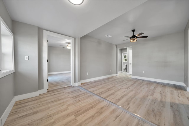 spare room featuring a fireplace, light hardwood / wood-style flooring, and ceiling fan