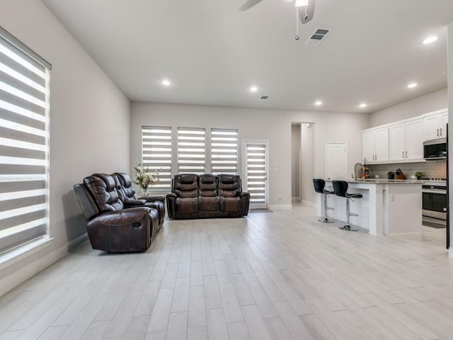 living room featuring ceiling fan and light wood-type flooring