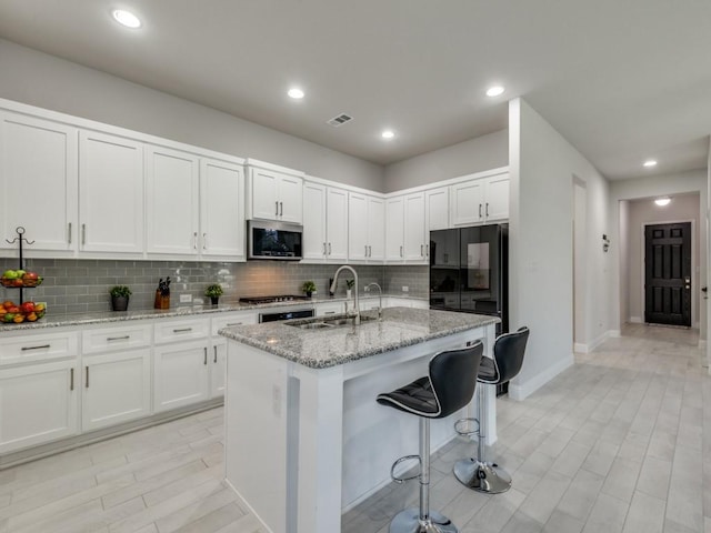 kitchen with sink, a center island with sink, white cabinets, and appliances with stainless steel finishes