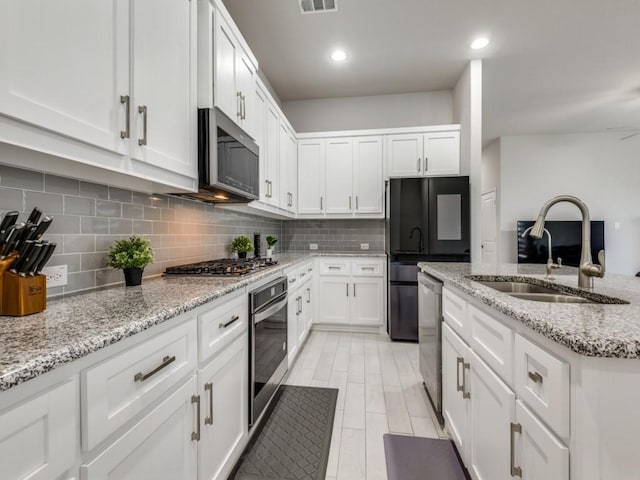 kitchen with white cabinetry, stainless steel appliances, sink, and light stone counters