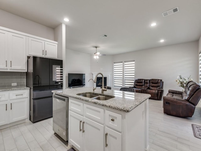 kitchen featuring sink, stainless steel appliances, white cabinets, and a center island with sink