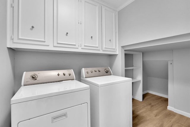 laundry area with cabinets, crown molding, washing machine and clothes dryer, and light wood-type flooring