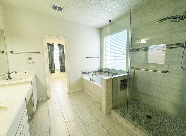 bathroom featuring a textured ceiling, vanity, and shower with separate bathtub