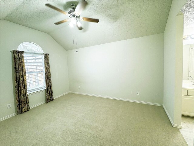 carpeted empty room with ceiling fan, a textured ceiling, and vaulted ceiling