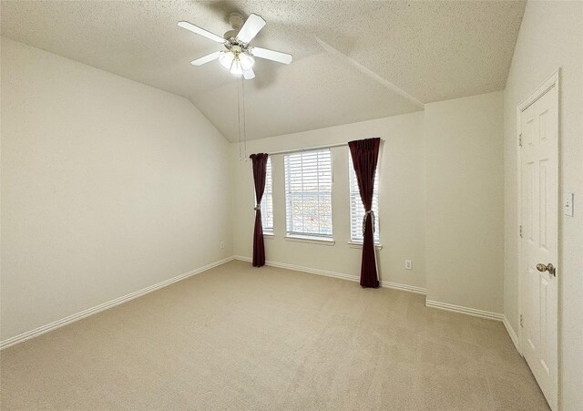 unfurnished room with a textured ceiling, ceiling fan, light colored carpet, and vaulted ceiling