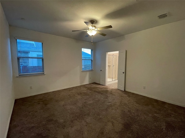 spare room featuring dark carpet and ceiling fan