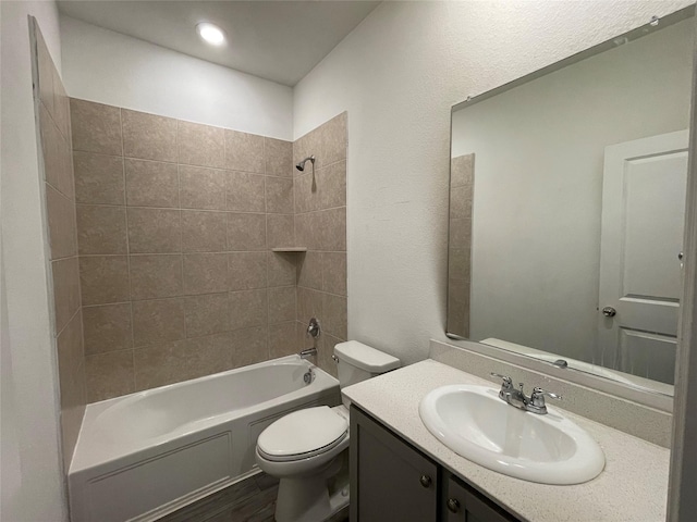 full bathroom featuring tiled shower / bath combo, vanity, wood-type flooring, and toilet