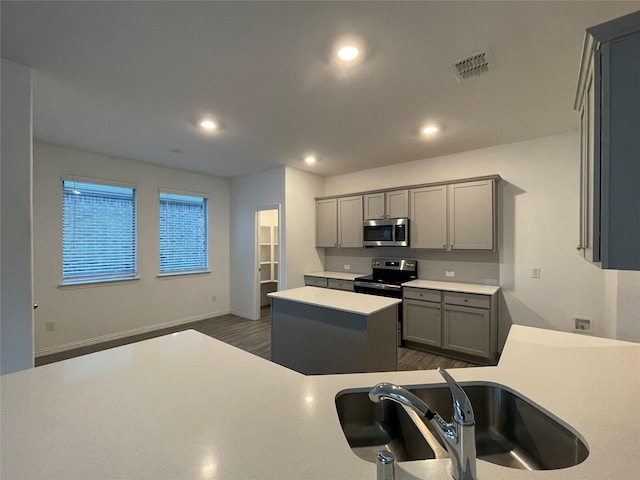 kitchen featuring stainless steel appliances, a kitchen island, gray cabinets, and sink