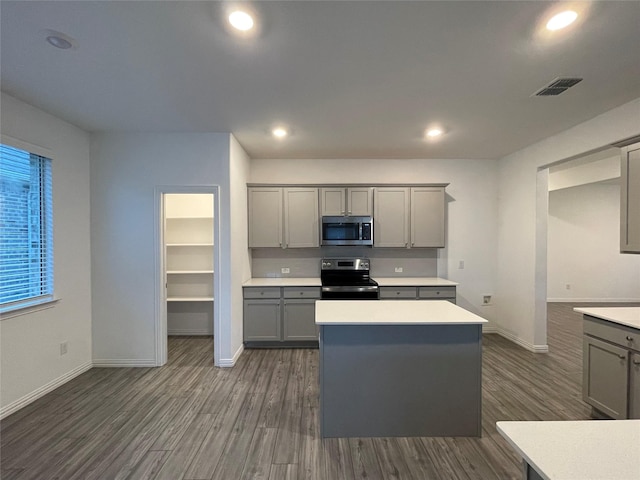 kitchen featuring stainless steel appliances, dark hardwood / wood-style flooring, gray cabinets, and a kitchen island