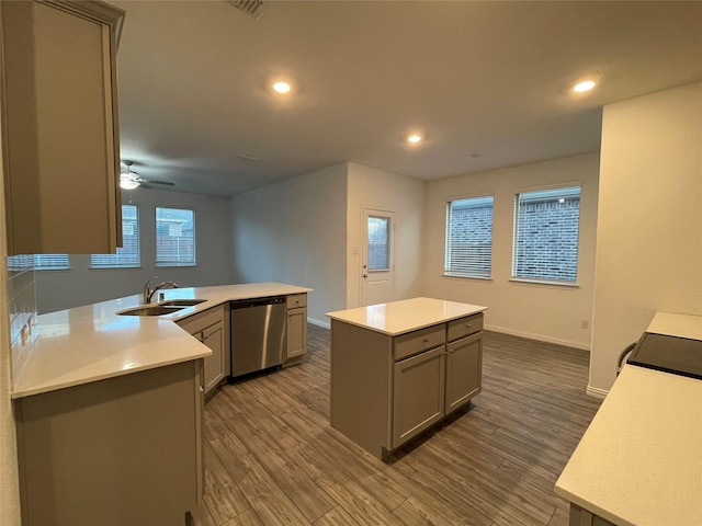 kitchen with sink, gray cabinetry, wood-type flooring, a kitchen island, and stainless steel dishwasher