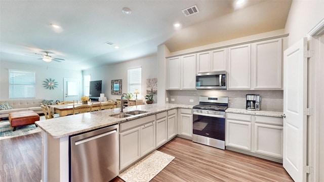 kitchen featuring ceiling fan, sink, light hardwood / wood-style flooring, kitchen peninsula, and appliances with stainless steel finishes