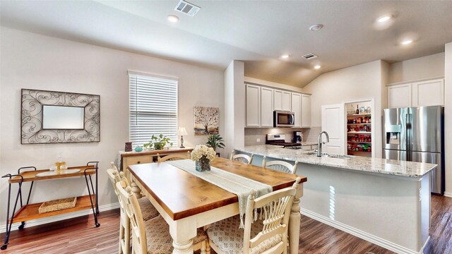 dining room featuring sink, hardwood / wood-style floors, and lofted ceiling