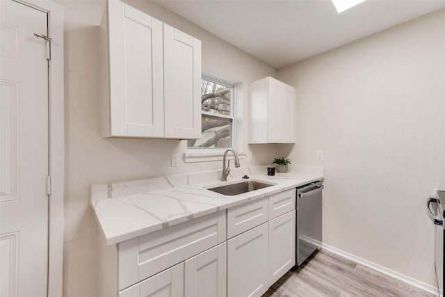 kitchen with dishwasher, sink, white cabinets, light stone countertops, and light hardwood / wood-style flooring