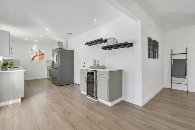 kitchen featuring wine cooler, light wood-type flooring, sink, and stainless steel refrigerator