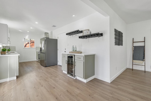 kitchen featuring beverage cooler, light wood-style flooring, a sink, and freestanding refrigerator